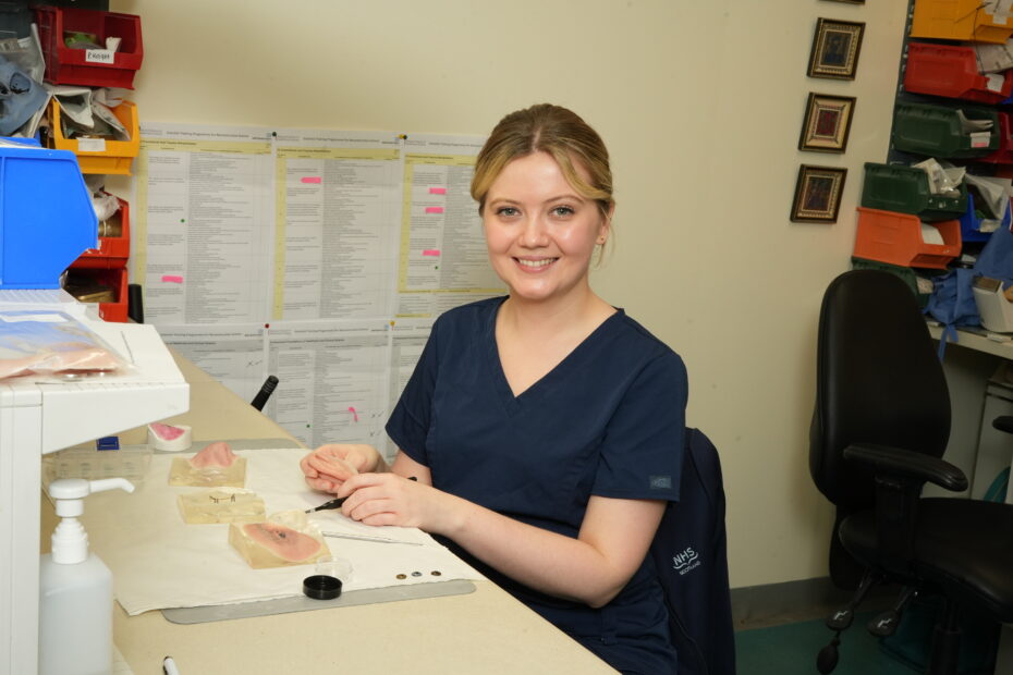 Danielle Adair sitting at her desk, working on prosthetics for patients.